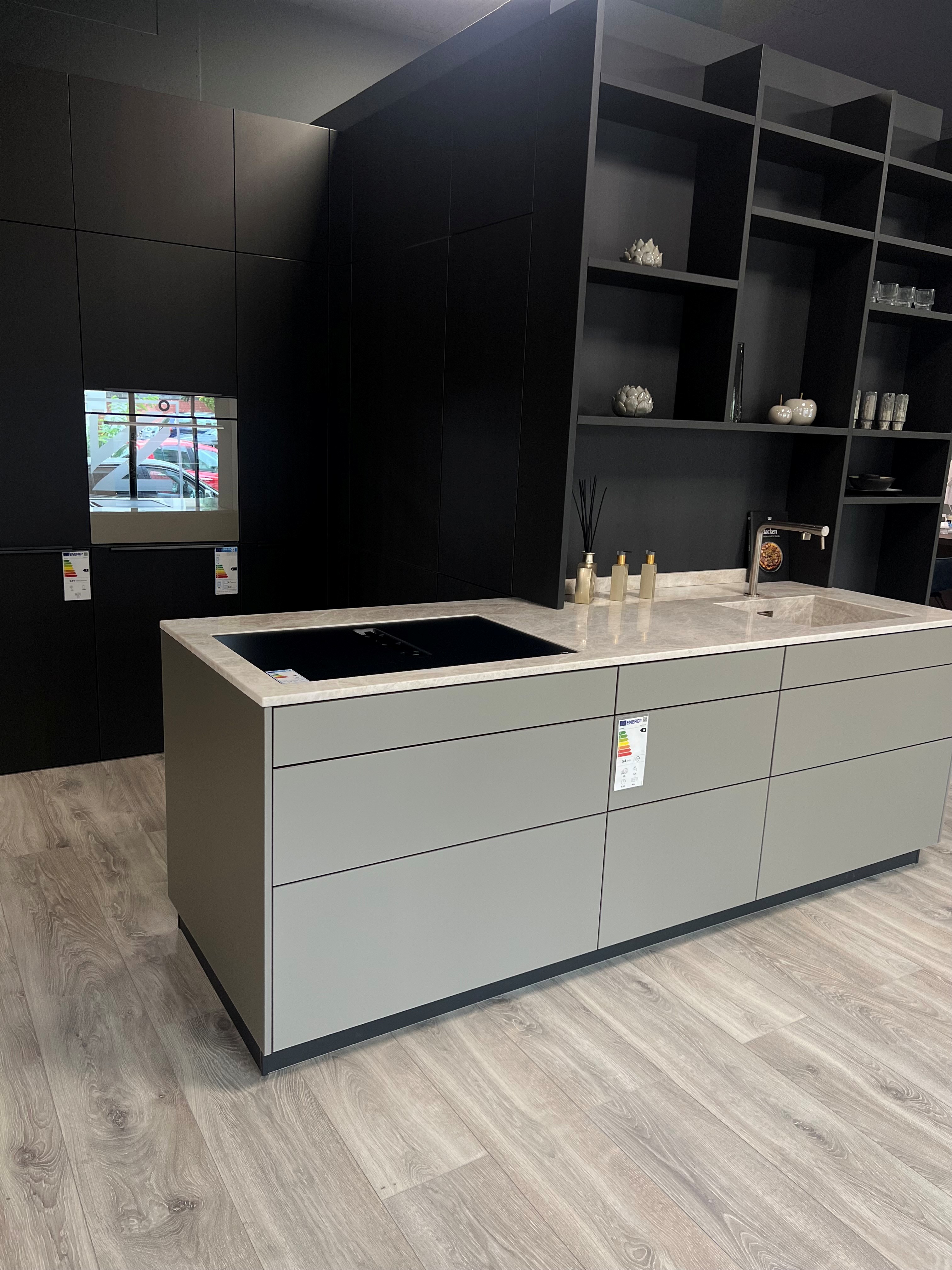 Kücheninsel grau grifflos vor Küchenzeile schwarz grifflos und Regalwand schwarz